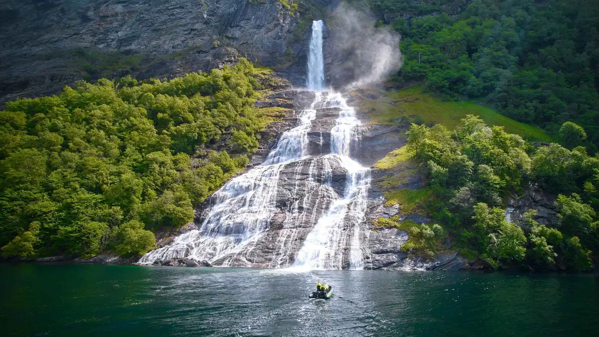 Guided RIB boat beneath a waterfall during a 75-minute Geiranger fjord cruise boat tour in Norway